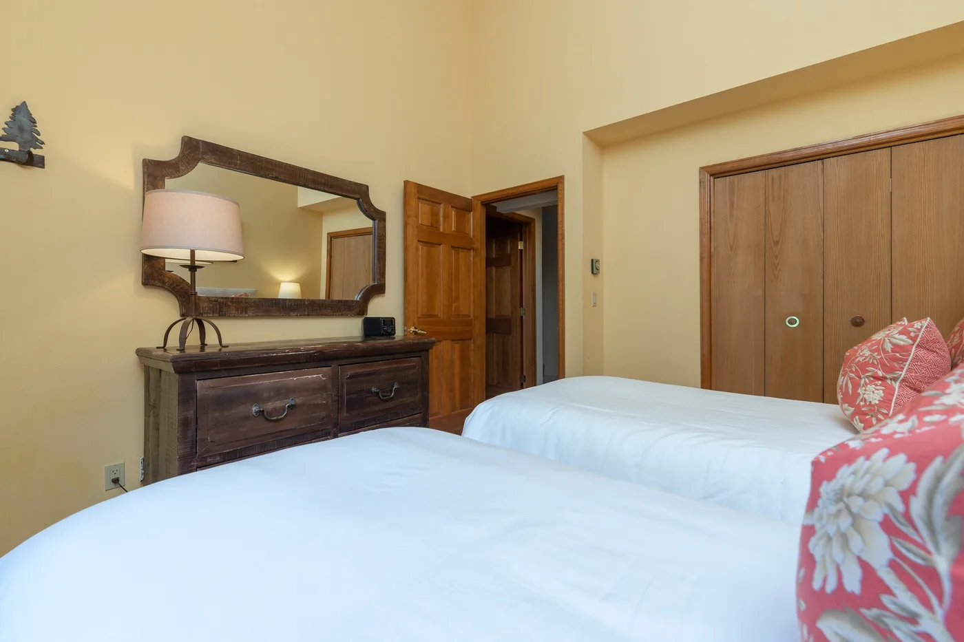 A bedroom with two beds, a wooden dresser, and a large mirror.