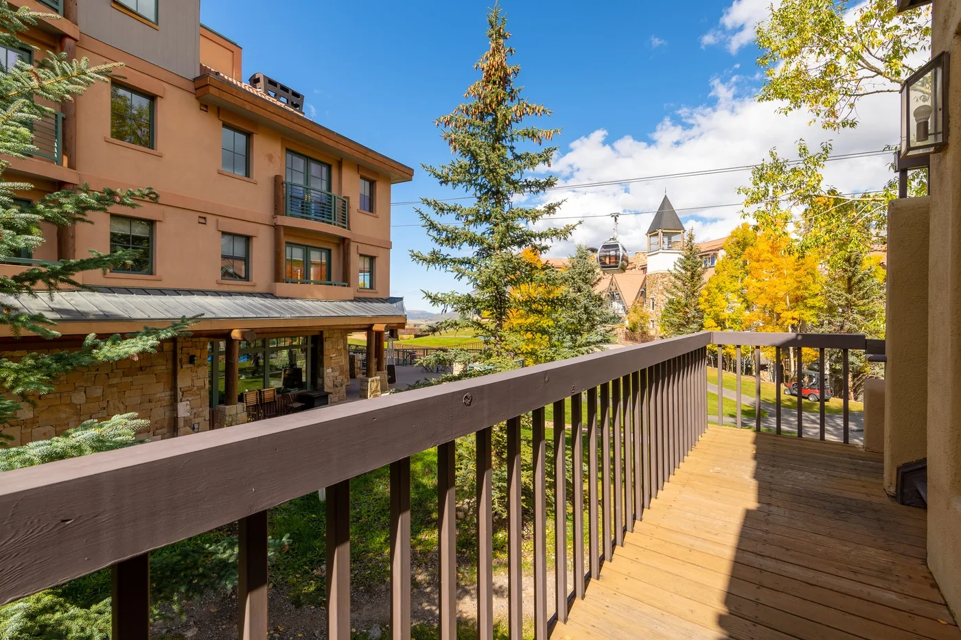A wooden balcony overlooks a landscaped courtyard and nearby buildings.