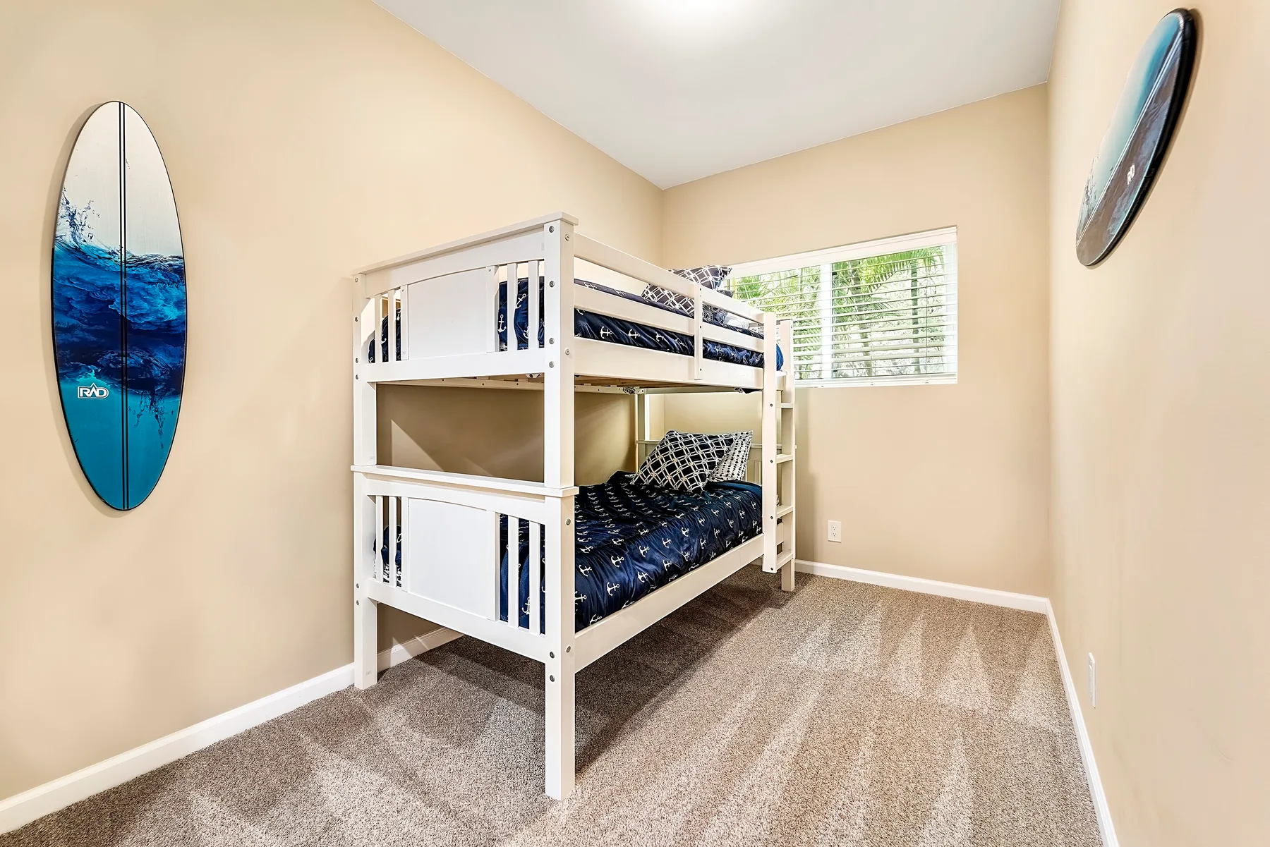 Un dormitorio con literas blancas y ropa de cama azul junto a una ventana.