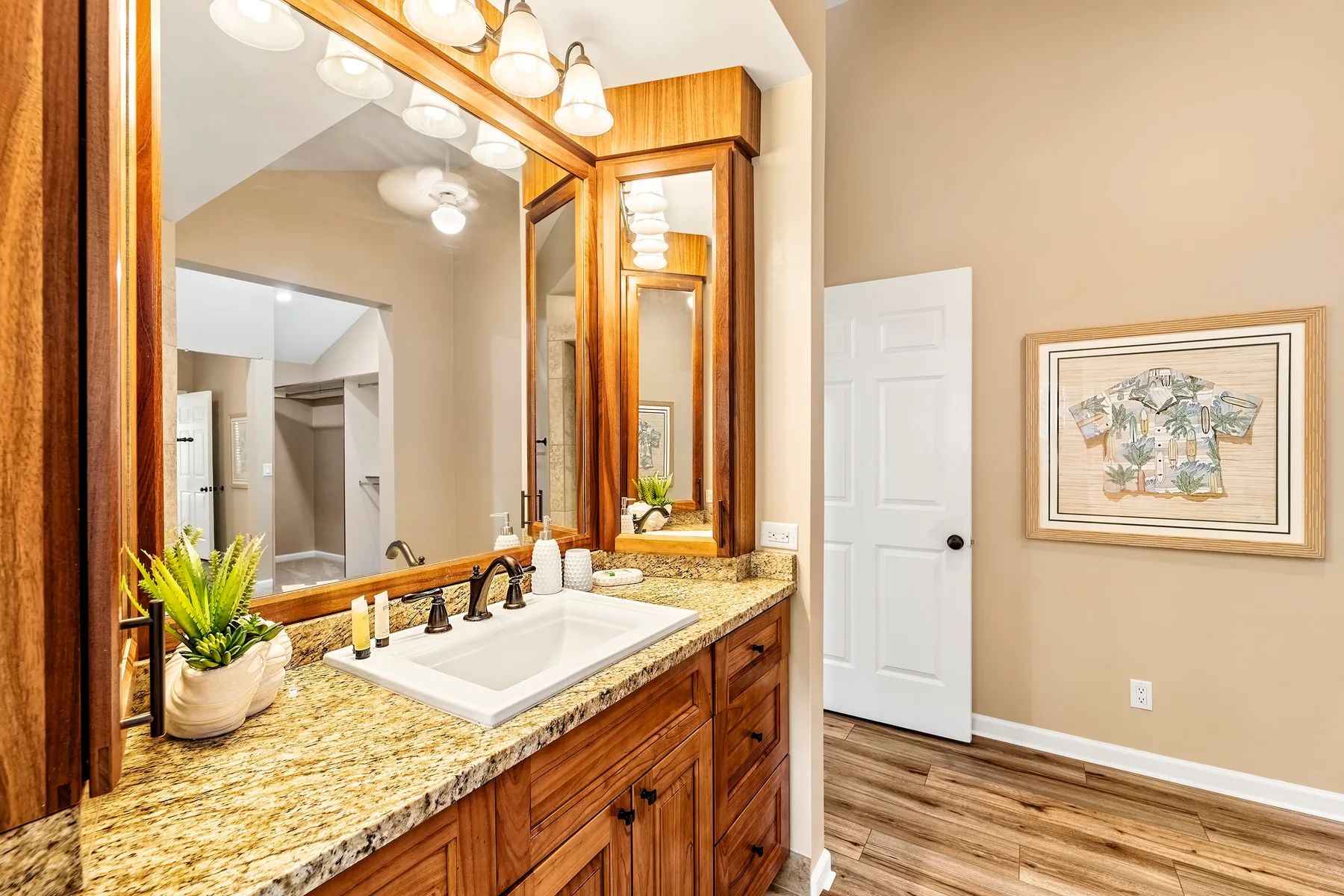 Un tocador de baño con lavabo y espejo grande junto a una puerta cerrada.
