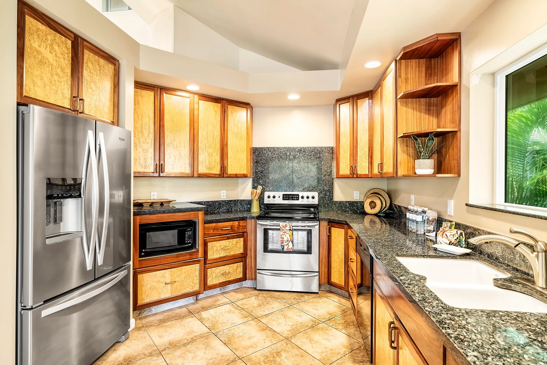 Una cocina luminosa con gabinetes de madera, electrodomésticos de acero inoxidable y encimeras de granito.