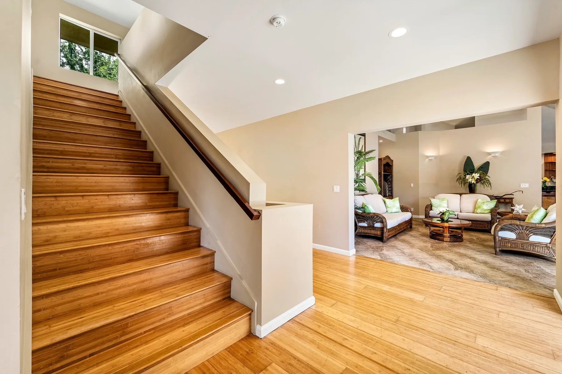 Una escalera da a una sala de estar con asientos y piso de madera.