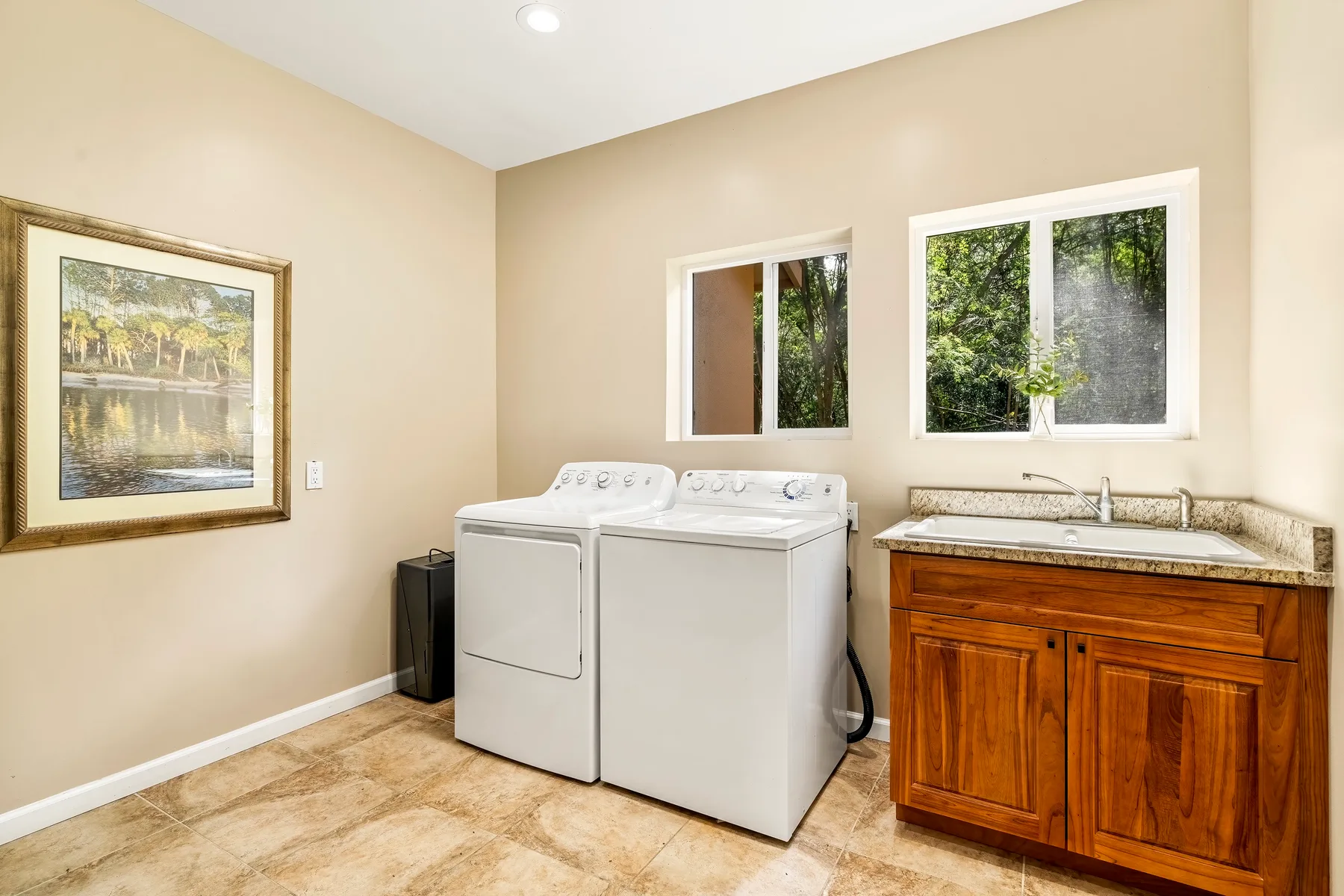 Un cuarto de lavandería con lavadora y secadora junto a un mueble de lavabo de madera.