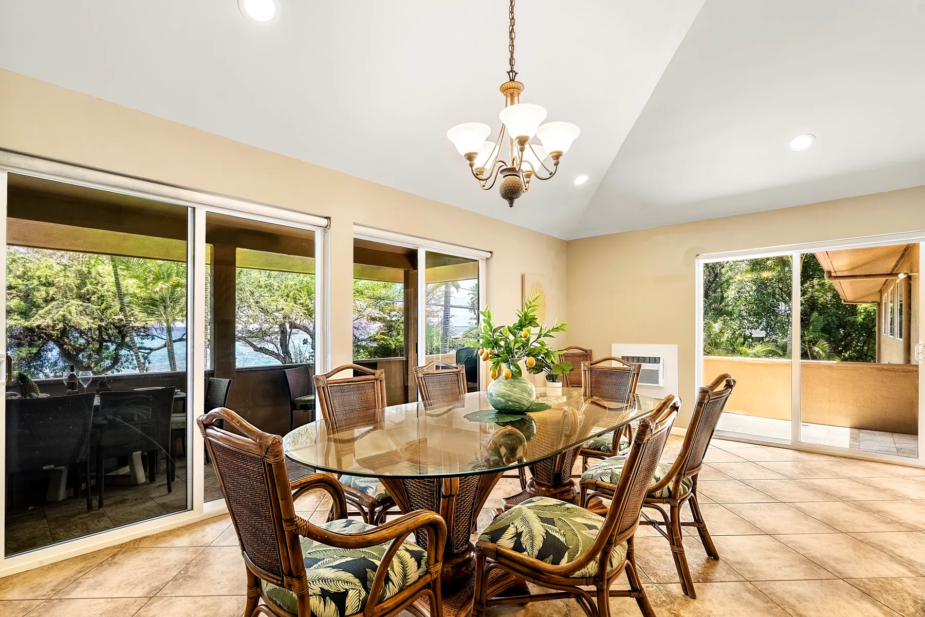 Un comedor luminoso con una mesa de vidrio y sillas junto a grandes ventanas.