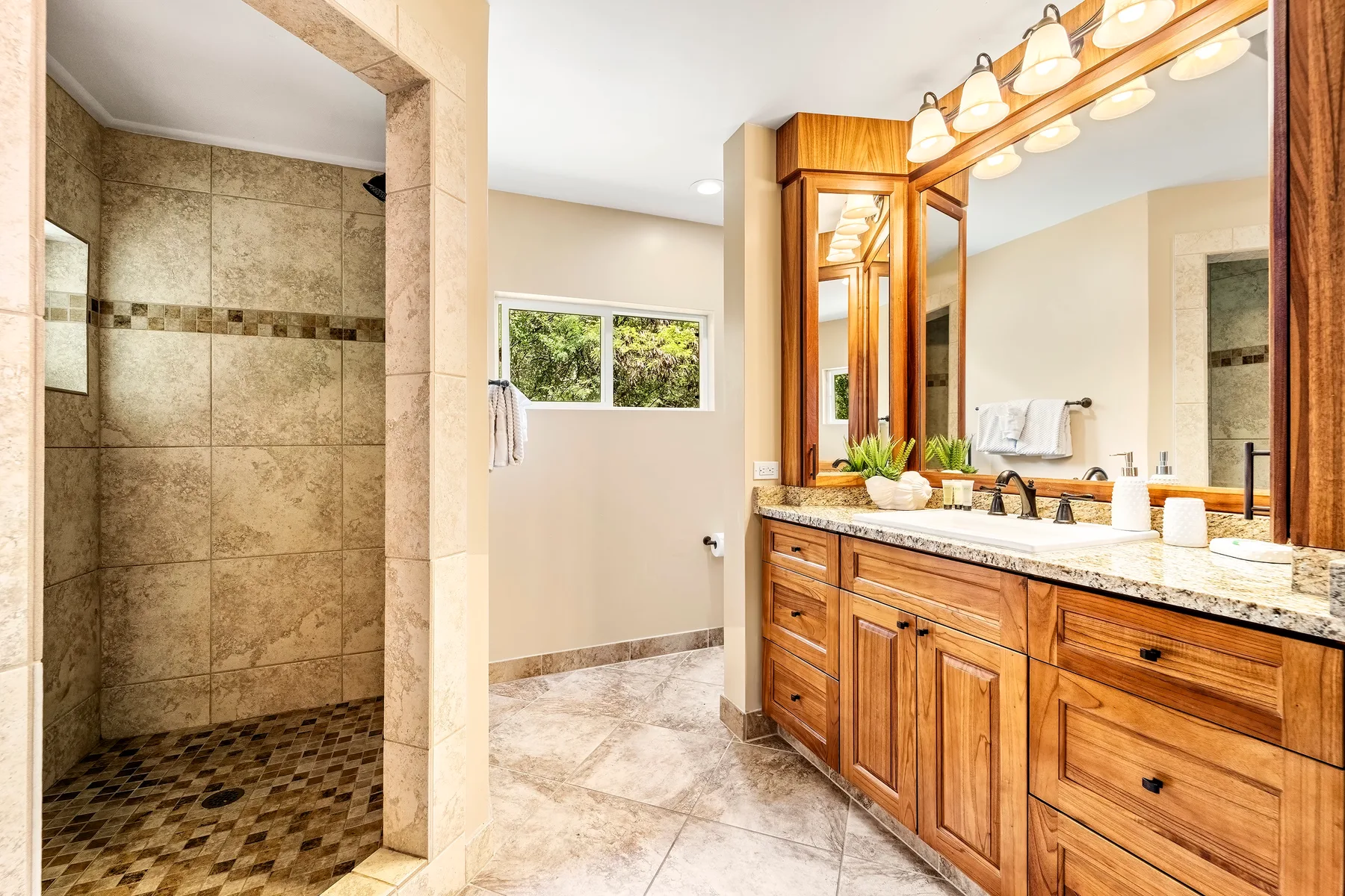Un baño con una ducha de azulejos y un largo mueble de madera bajo un espejo grande.