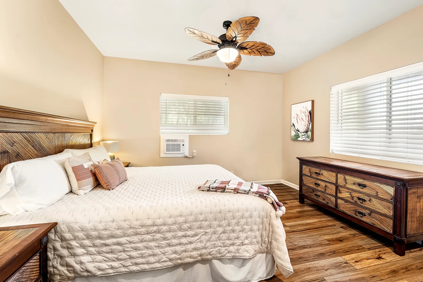 Un dormitorio con una cama grande, una cómoda y ventanas con persianas.