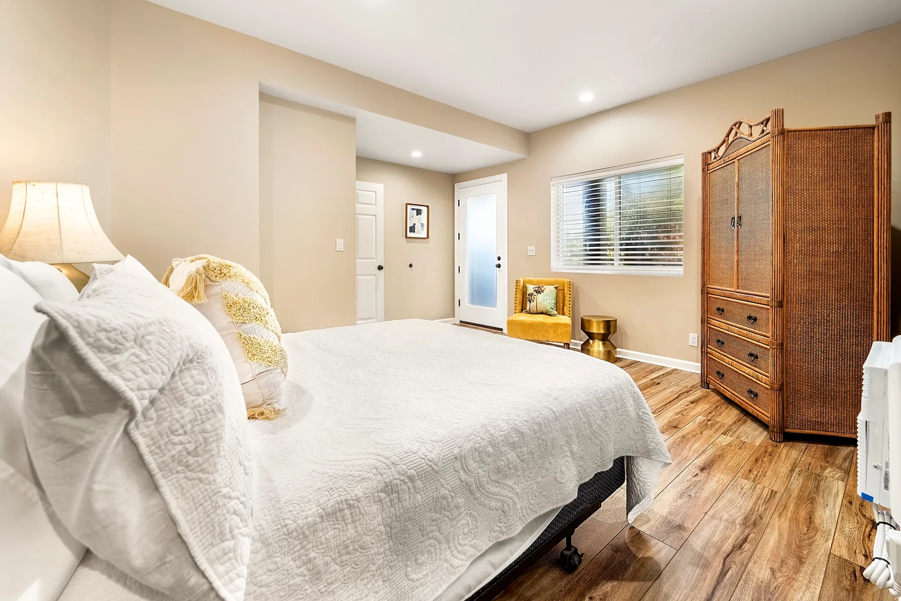 Un dormitorio luminoso con una cama, una ventana y un armario de madera.