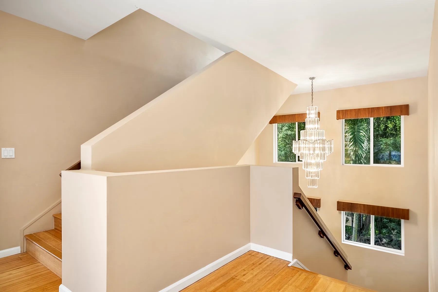 Una escalera y un suelo de madera se ven en un interior luminoso con ventanas altas.