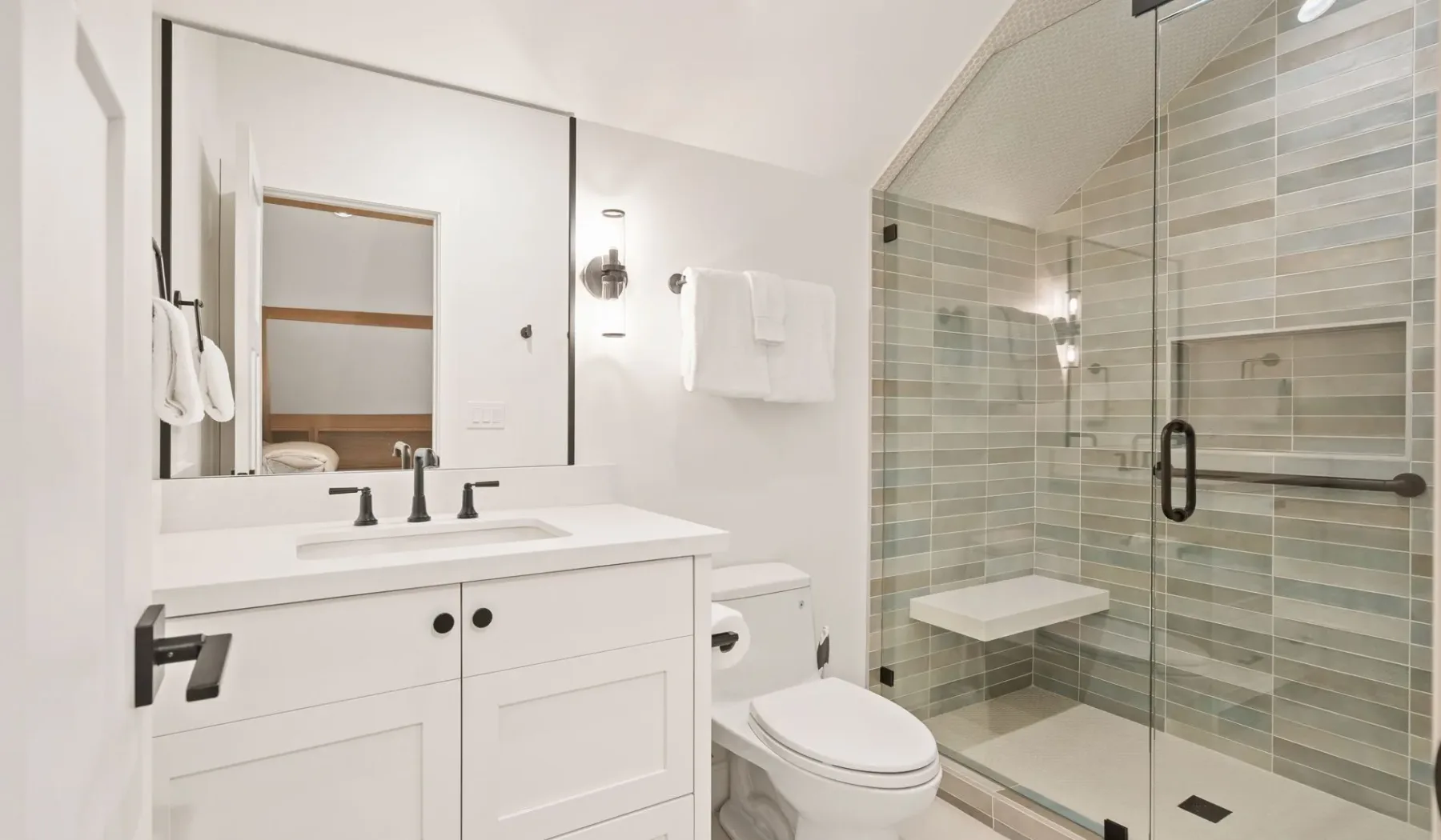 Un baño luminoso con tocador, inodoro y ducha con mampara de vidrio.