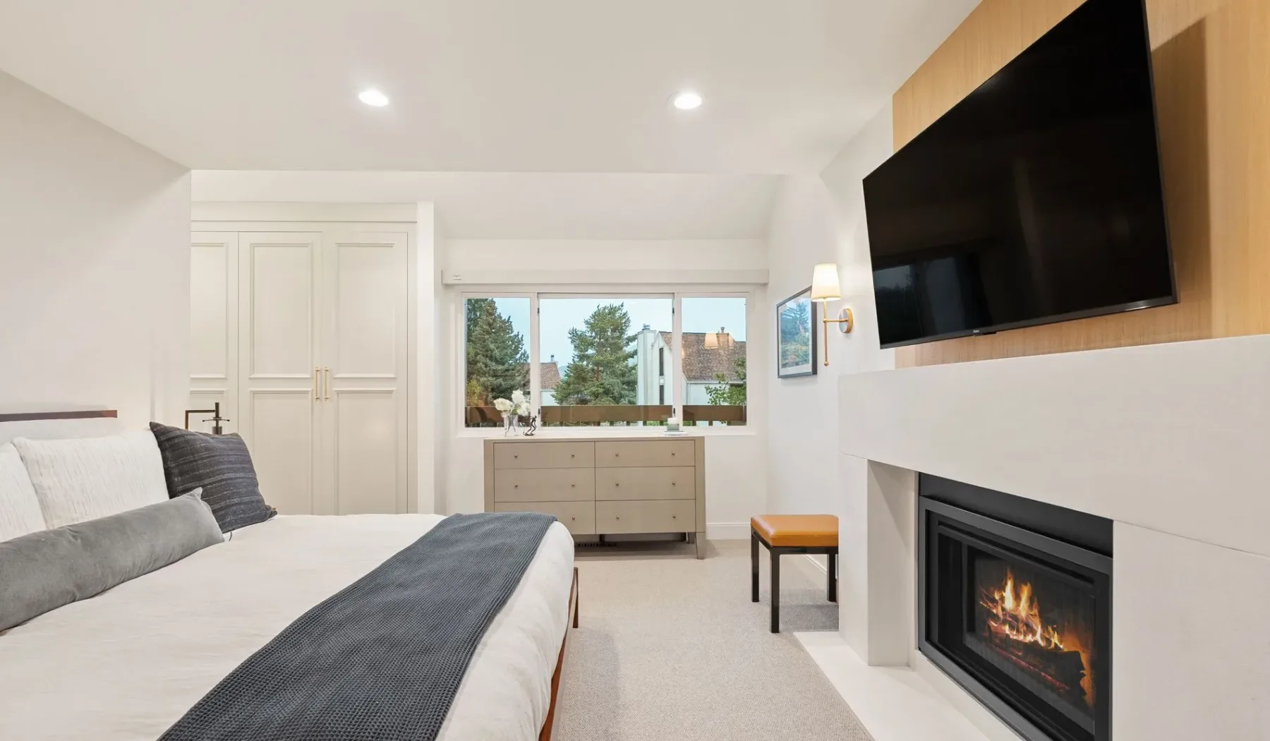 Un dormitorio luminoso con una cama, una ventana y una chimenea.