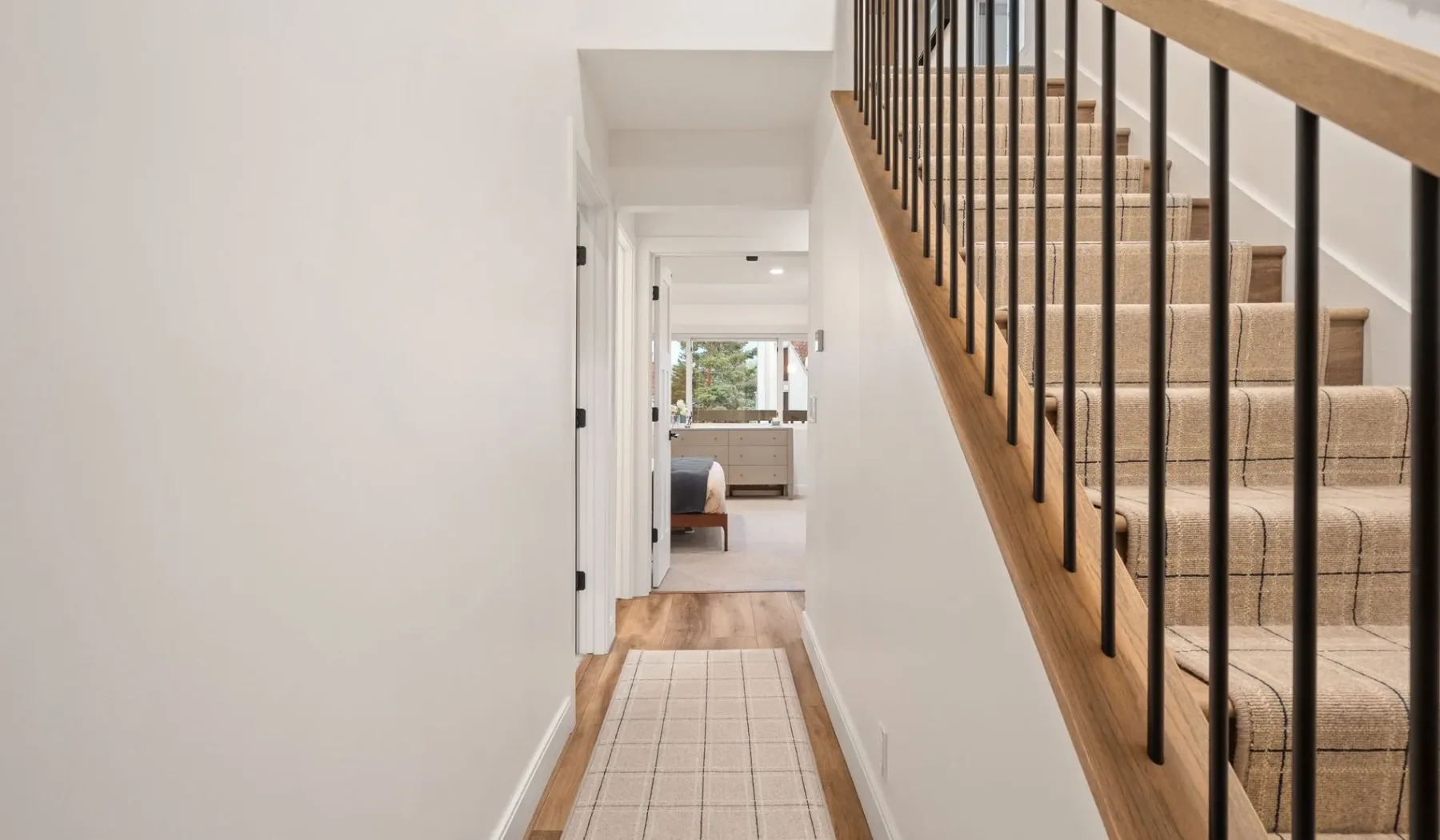 Un pasillo conduce a una sala de estar junto a una escalera.
