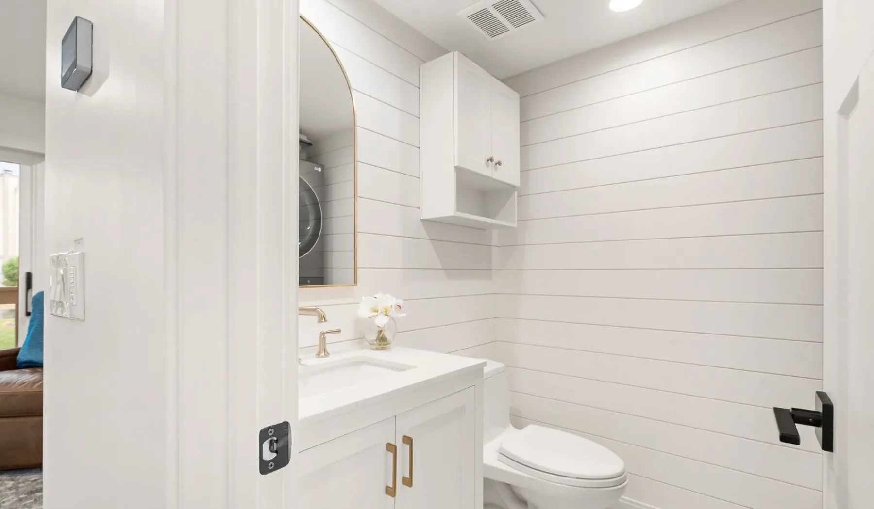 Un baño luminoso con un tocador blanco y un inodoro.