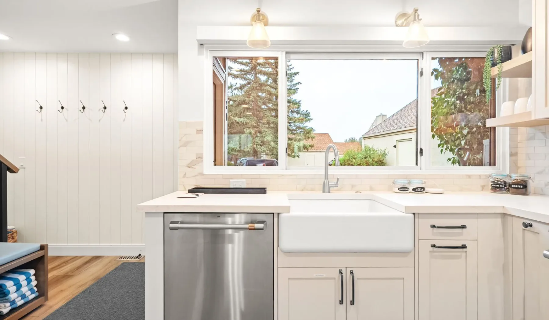 Una cocina luminosa con un fregadero de estilo granja bajo una ventana amplia.