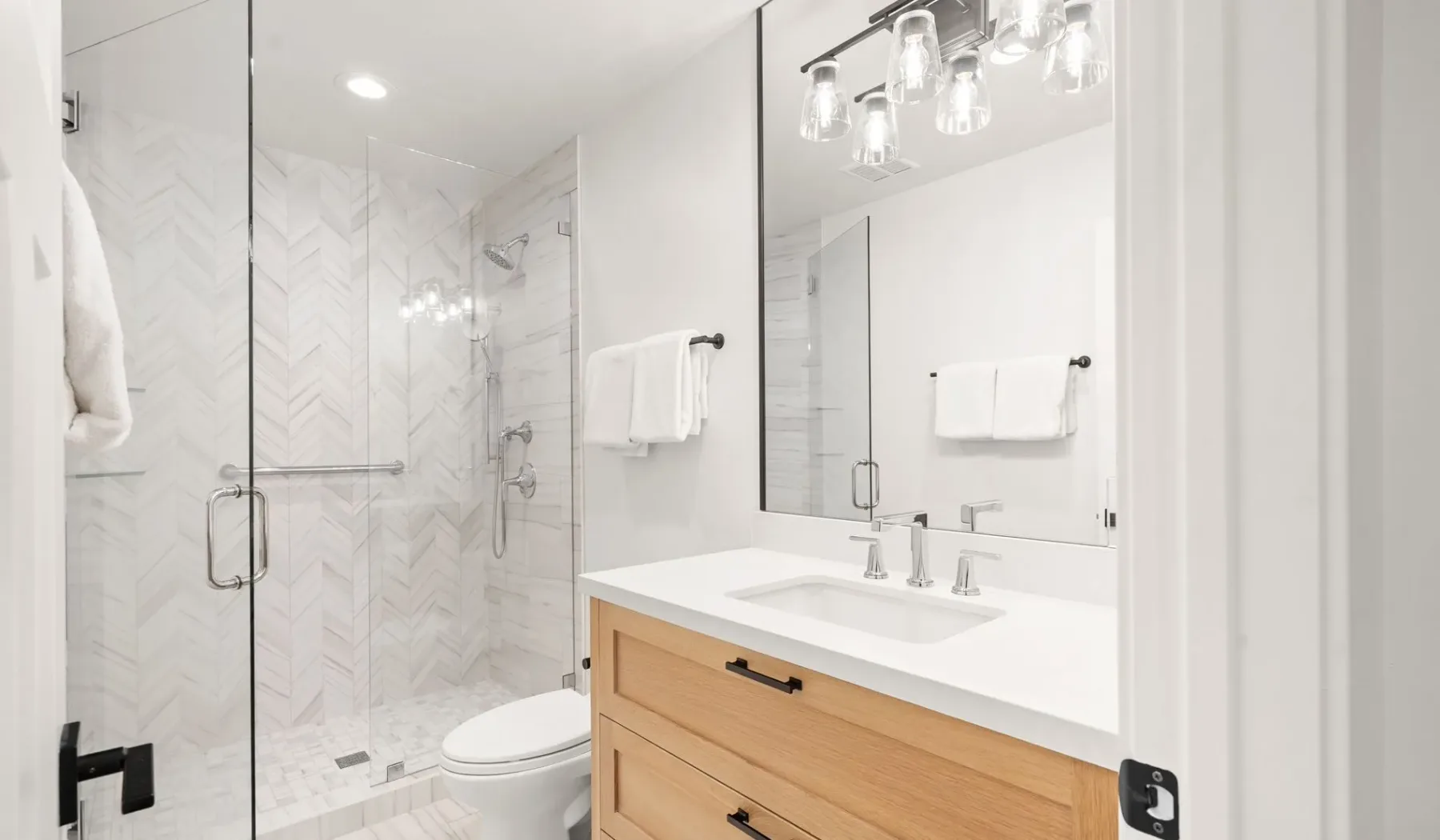 Un baño luminoso con ducha de vidrio y tocador.