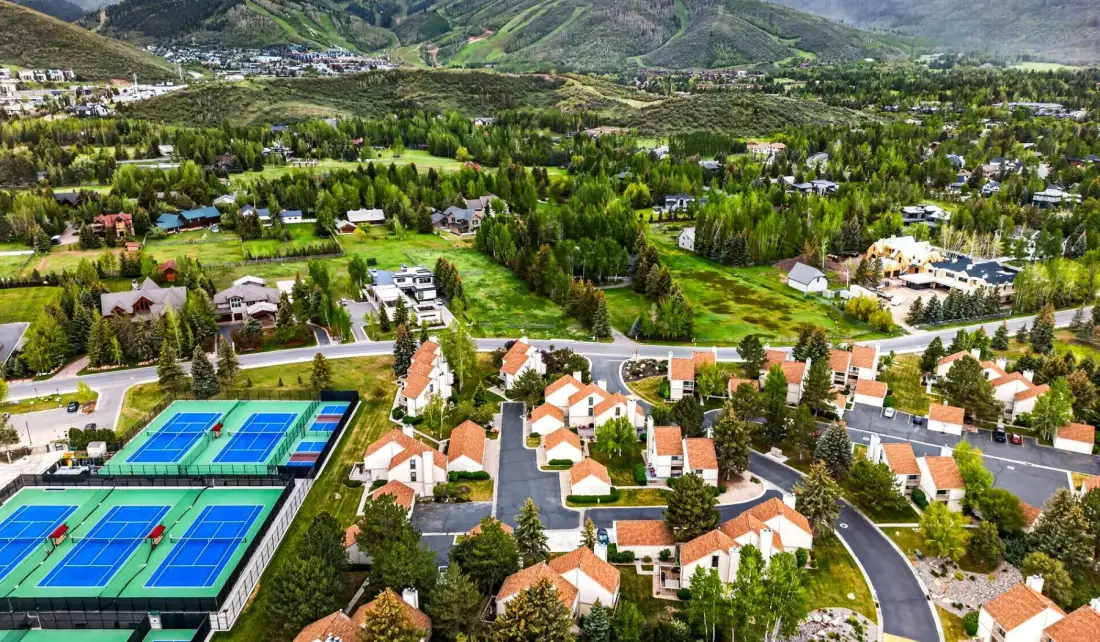 Vista aérea de un asentamiento en la ladera, con viviendas, campos verdes y canchas de tenis.