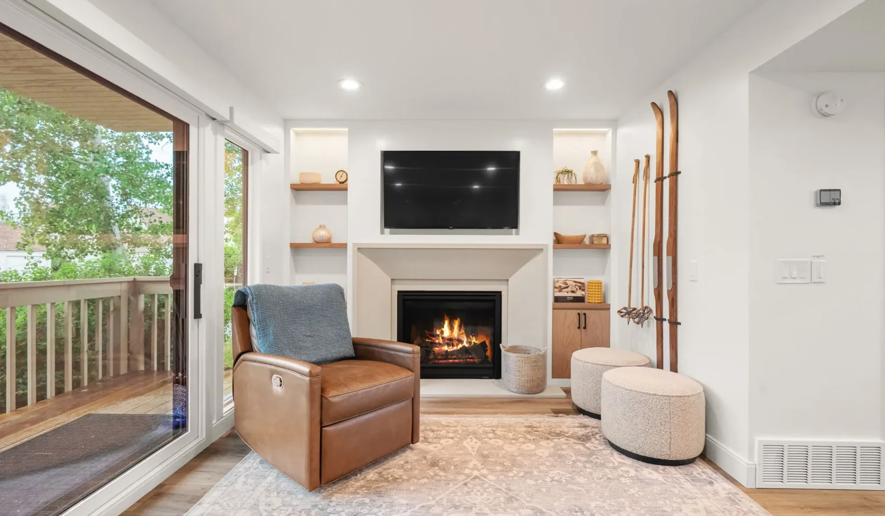 Una sala luminosa con chimenea, televisor y puertas corredizas de vidrio que dan a una terraza.