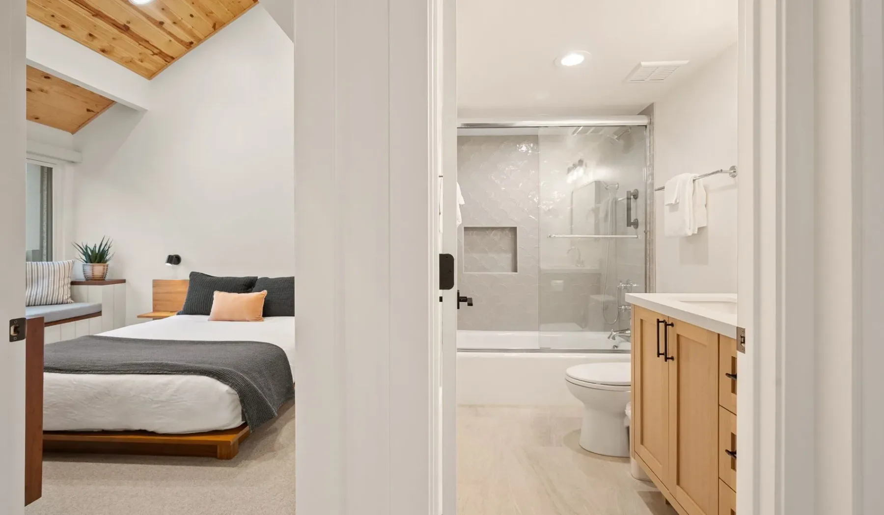 Un dormitorio con una cama junto a una puerta abierta hacia un baño.