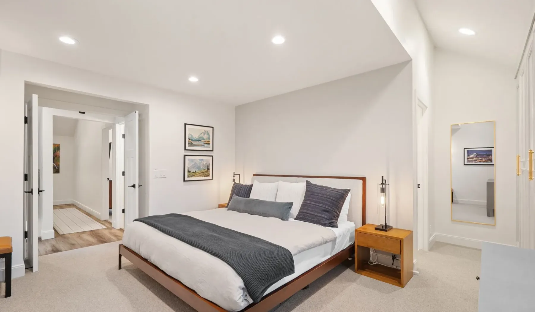 Un dormitorio con una cama, mesitas de noche y una puerta abierta.