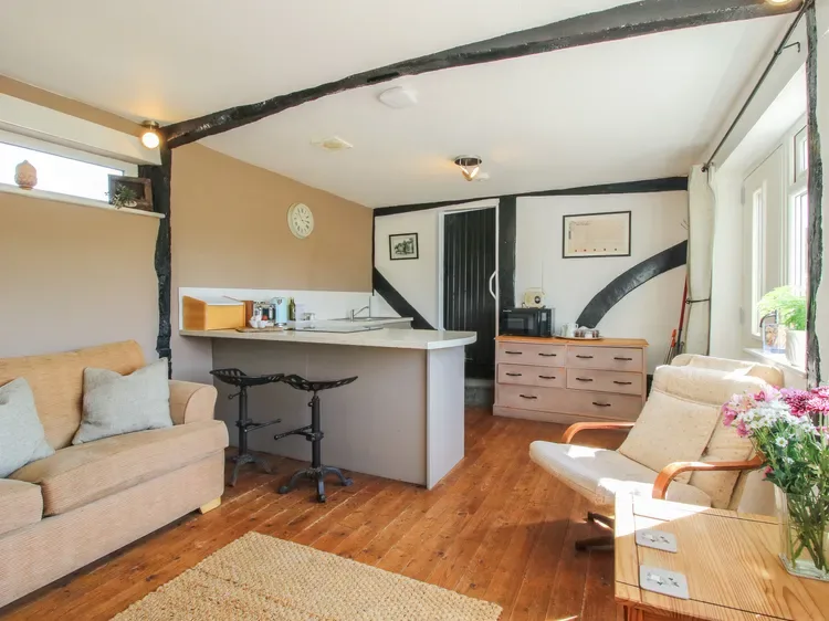 Una sala luminosa con una pequeña barra de cocina, asientos y ventanas grandes.