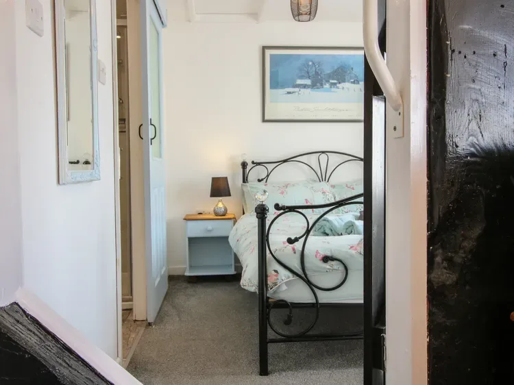 Un dormitorio con una cama de metal negro y una pequeña mesita de noche.