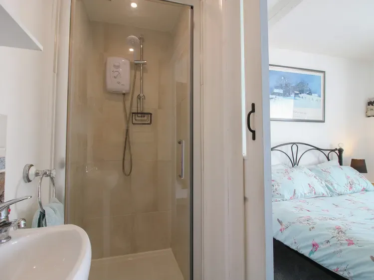 Una ducha de baño está junto a un dormitorio con ropa de cama floral.