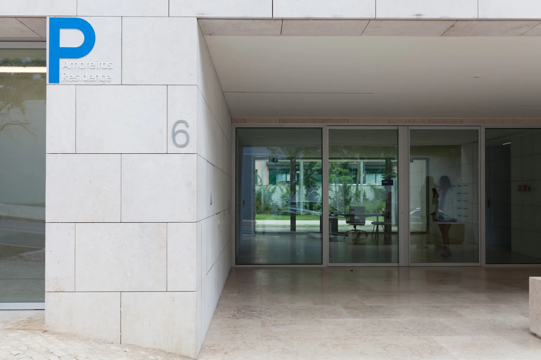 A building entrance with glass doors and a blue parking sign.
