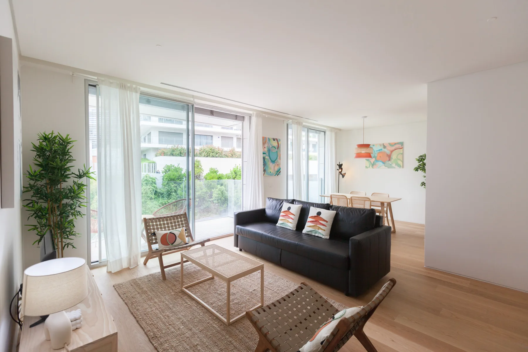 A bright living room with dark seating, a coffee table, and large windows.