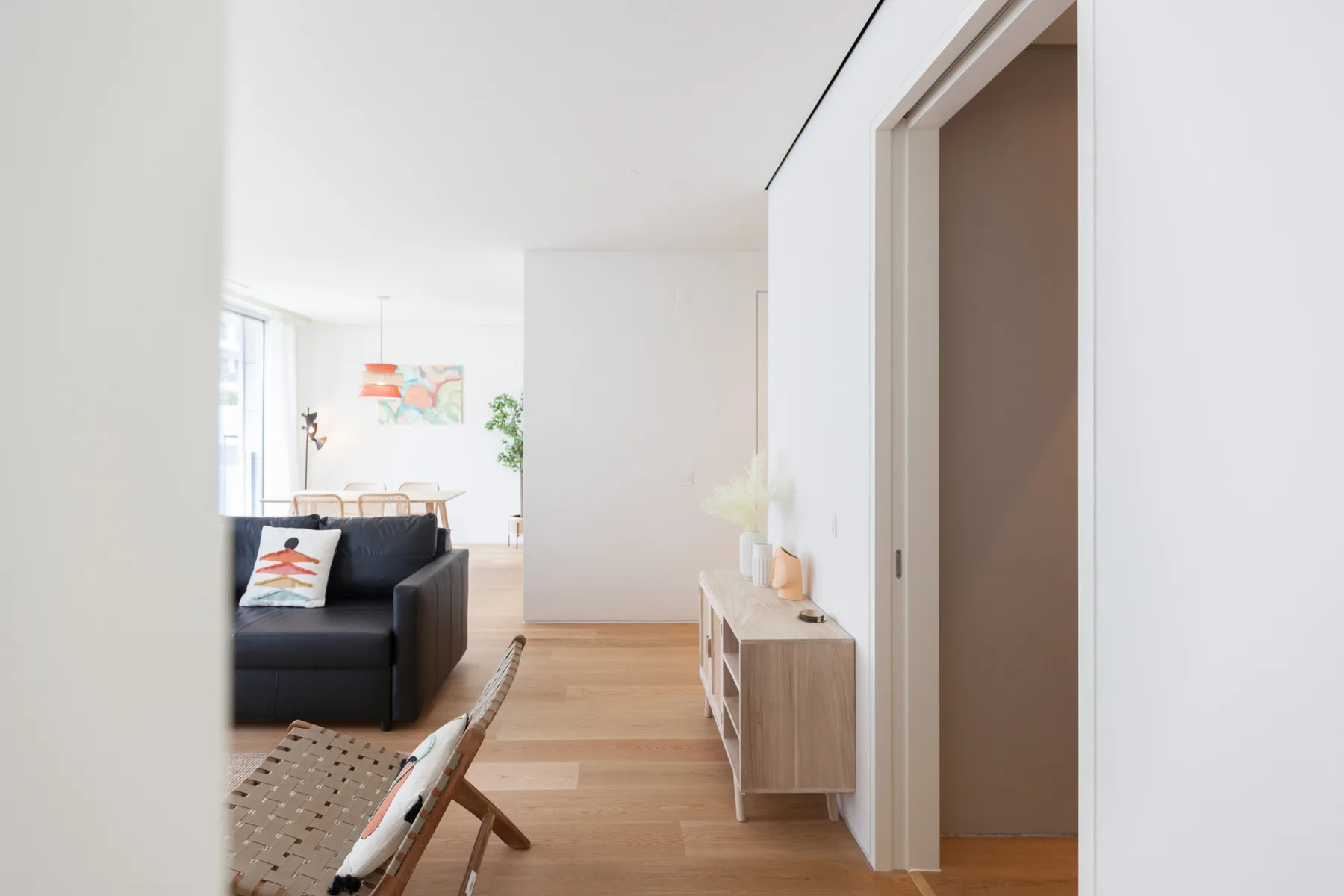A bright apartment interior with a hallway opening onto a living area.