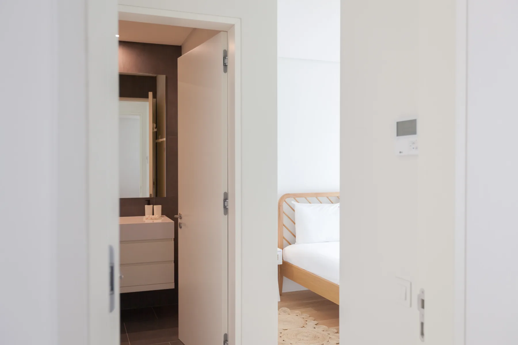 A bedroom with a bed is visible through an open doorway beside a bathroom.
