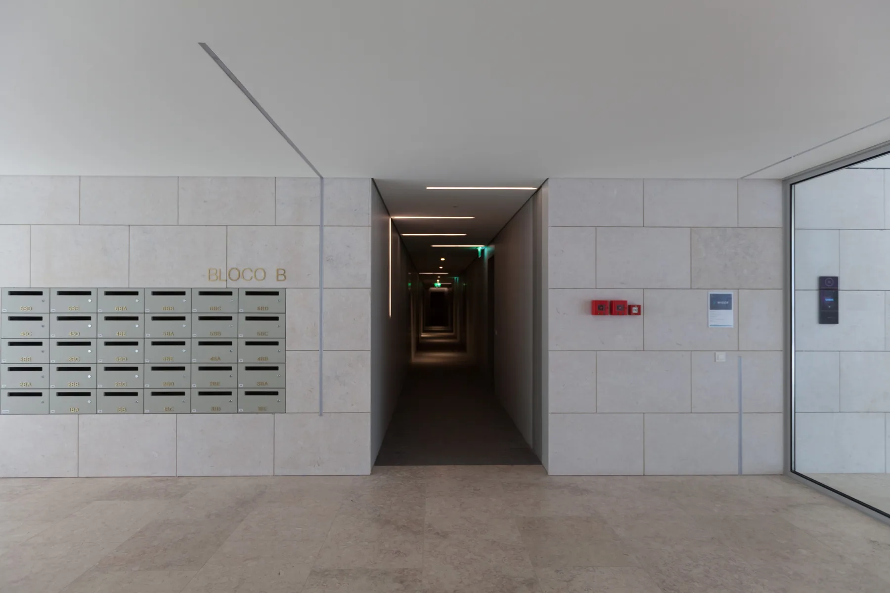 A building lobby with a row of mailboxes beside a long corridor.