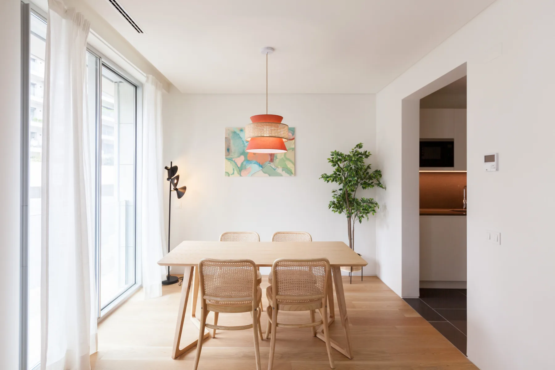A bright dining area with a wooden table, chairs, and large windows.