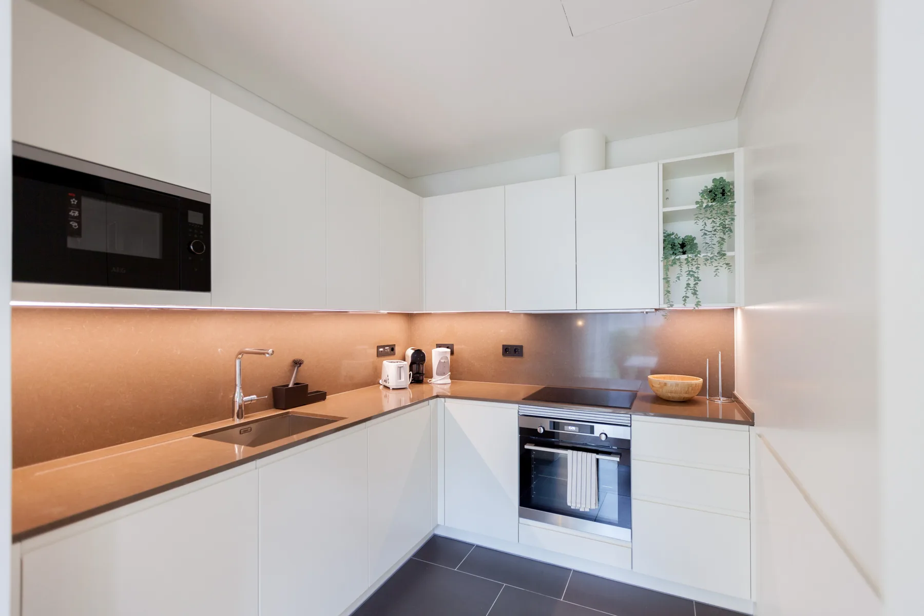 A modern kitchen with white cabinetry and a built-in oven.