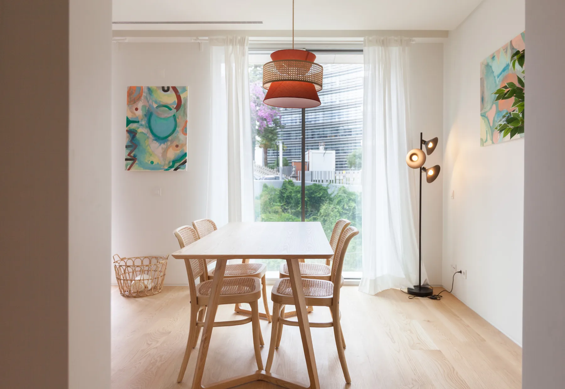 A bright dining area with a wooden table and chairs beside a large window.