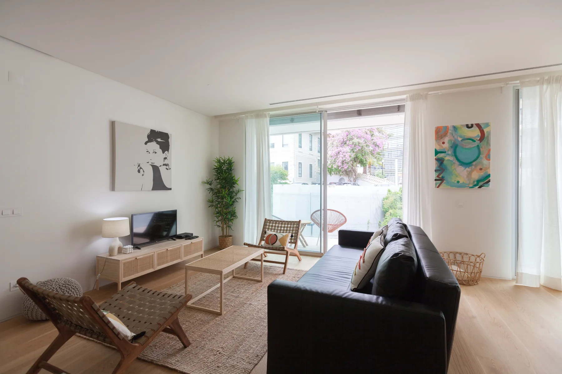 Living room with seating, a television, and large windows opening onto a balcony.