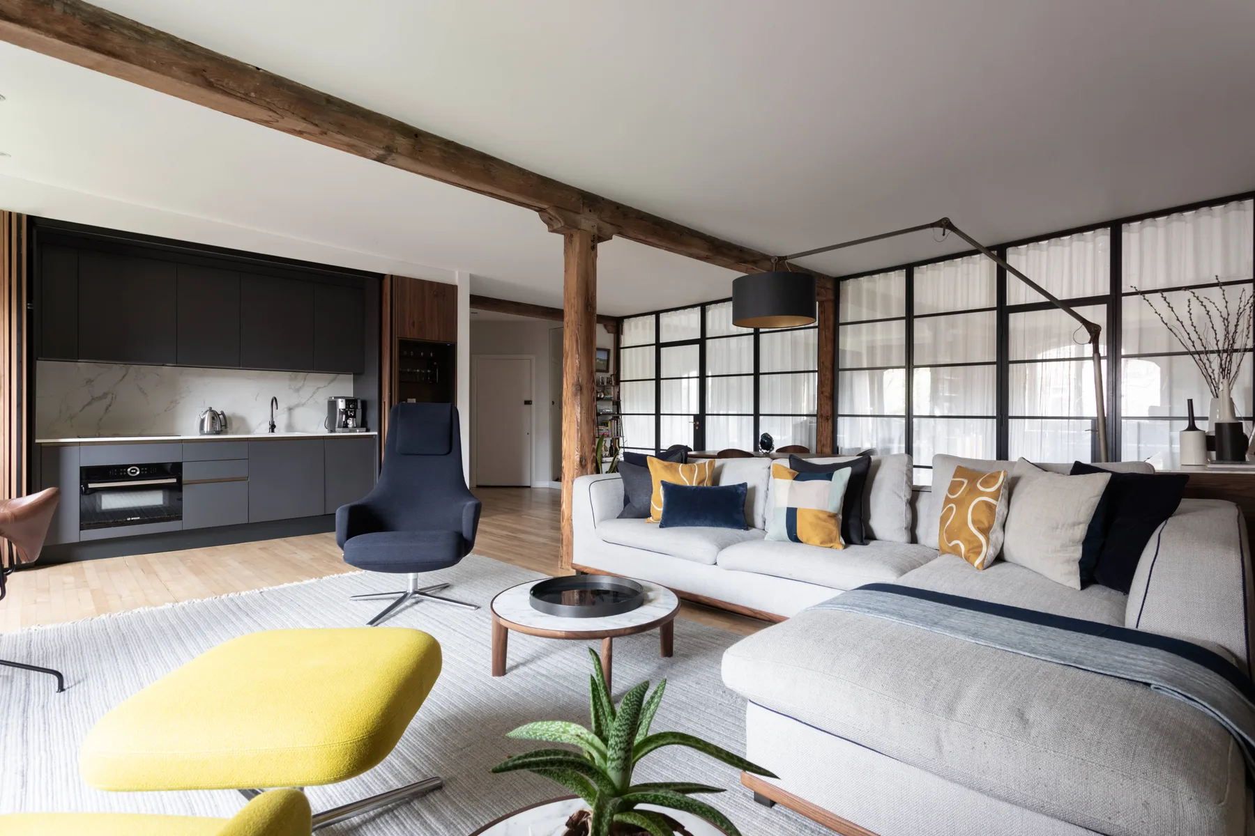 A modern open-plan living room with a sectional seating area and kitchen.