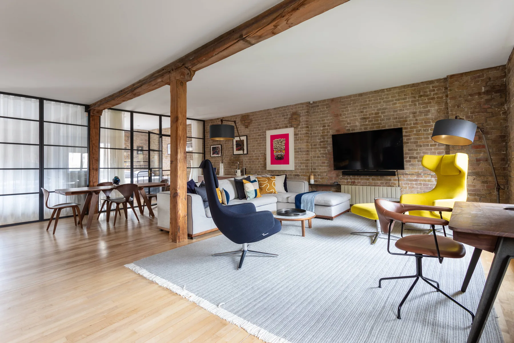 A bright living and dining area with seating beside large grid windows.