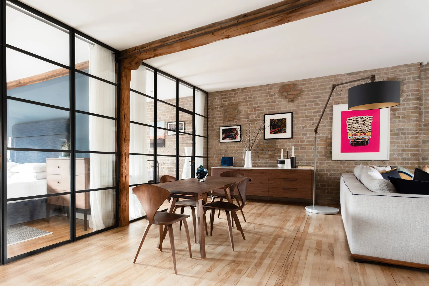 A dining and living area with a wooden table beside a brick wall.