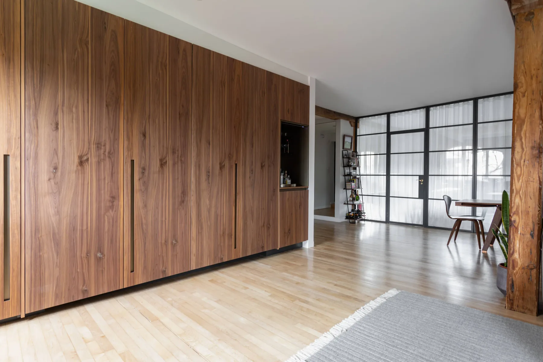 A bright living area with wood-paneled storage and large grid windows.