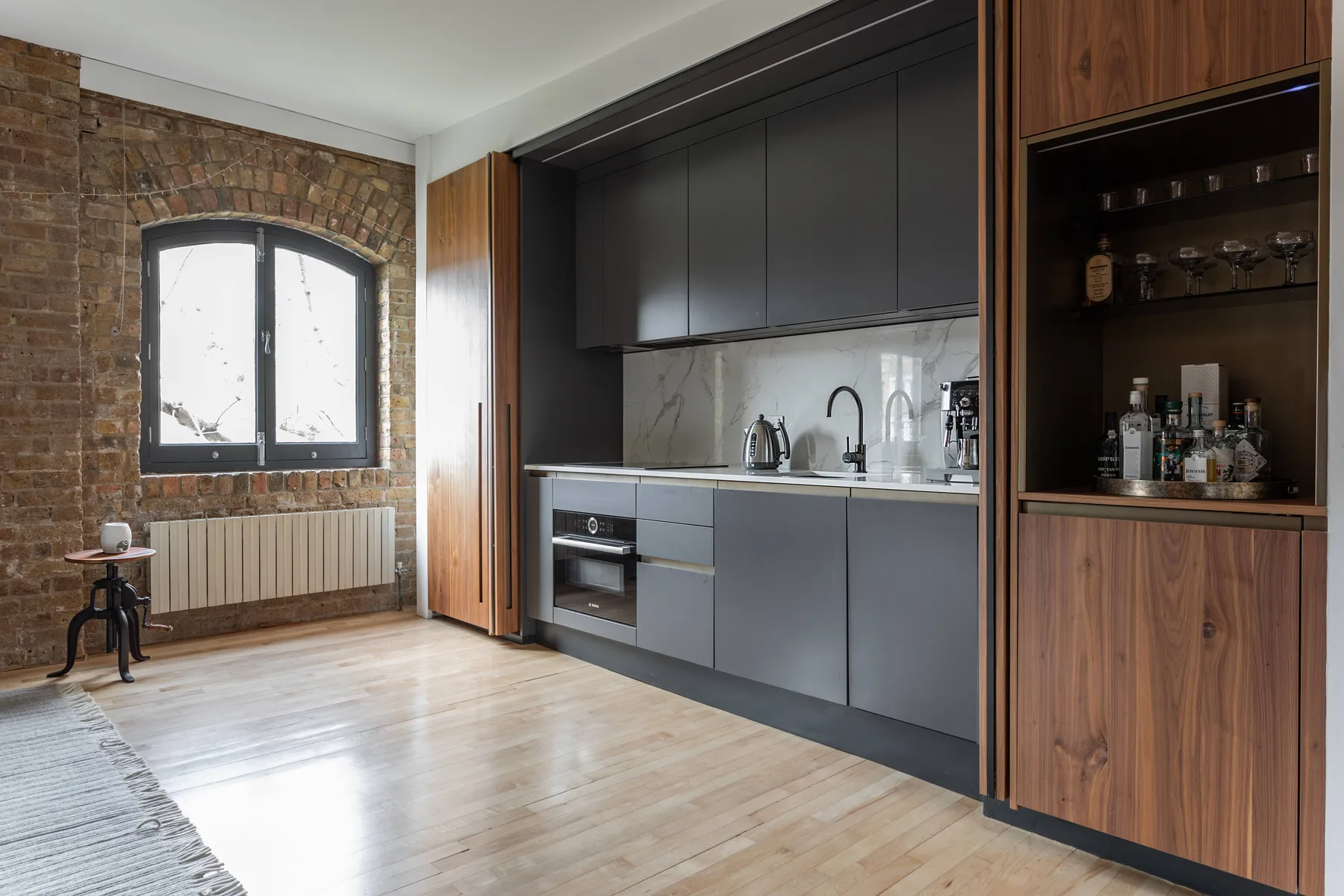 A modern kitchen with dark cabinets and a brick-framed window.