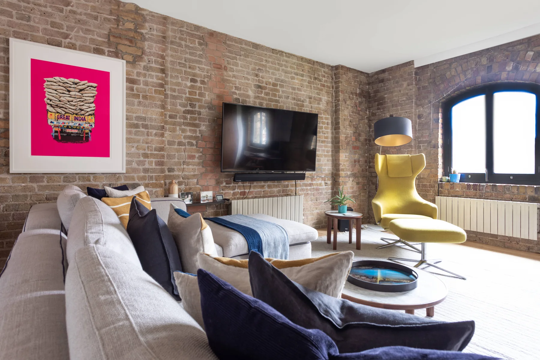 A living room with seating, a television, and a large arched window.