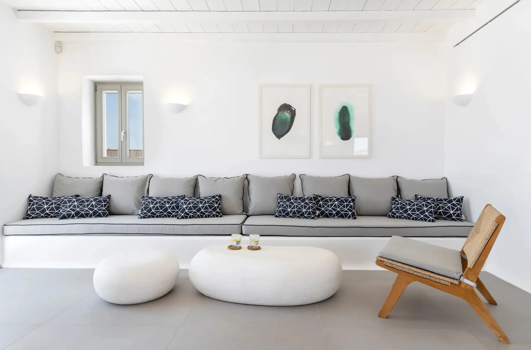 A bright living room with a long sofa and low white tables.