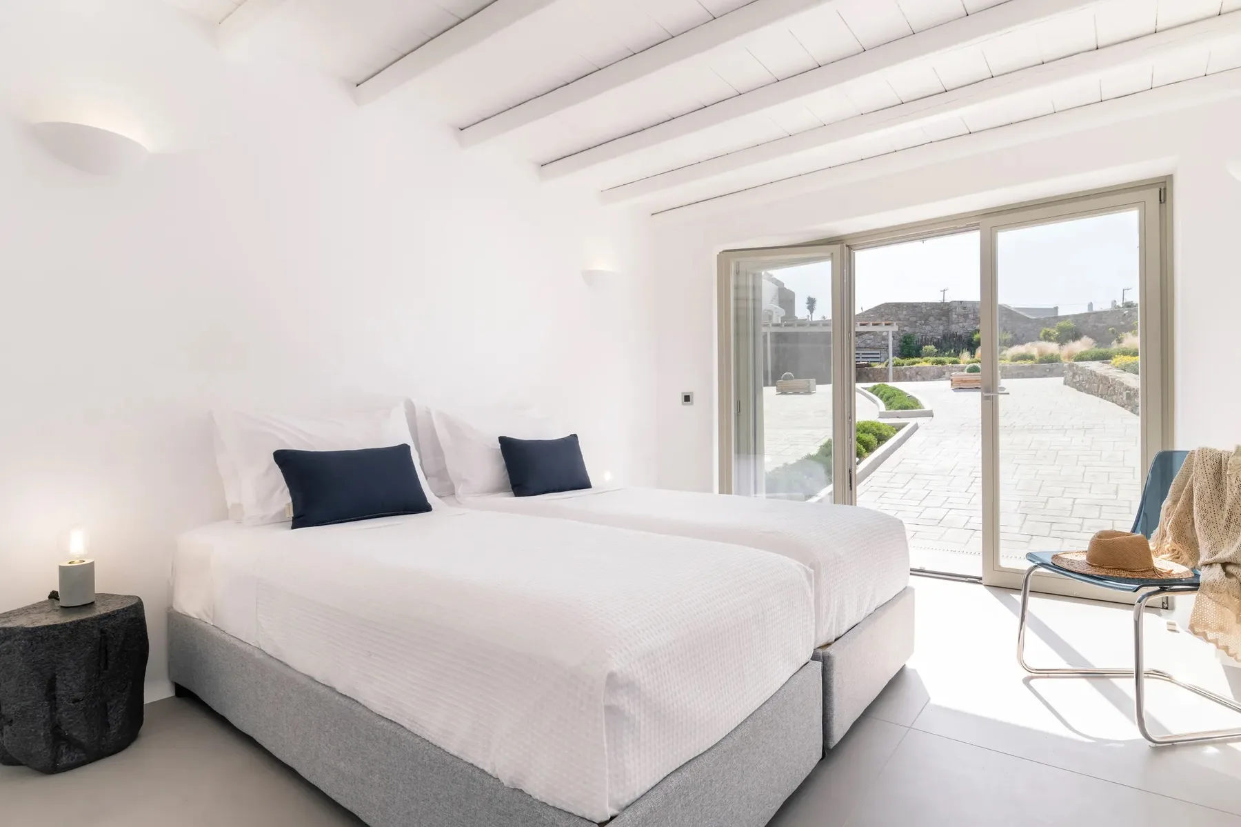 A bright bedroom with a large bed and sliding glass doors opening onto a patio.