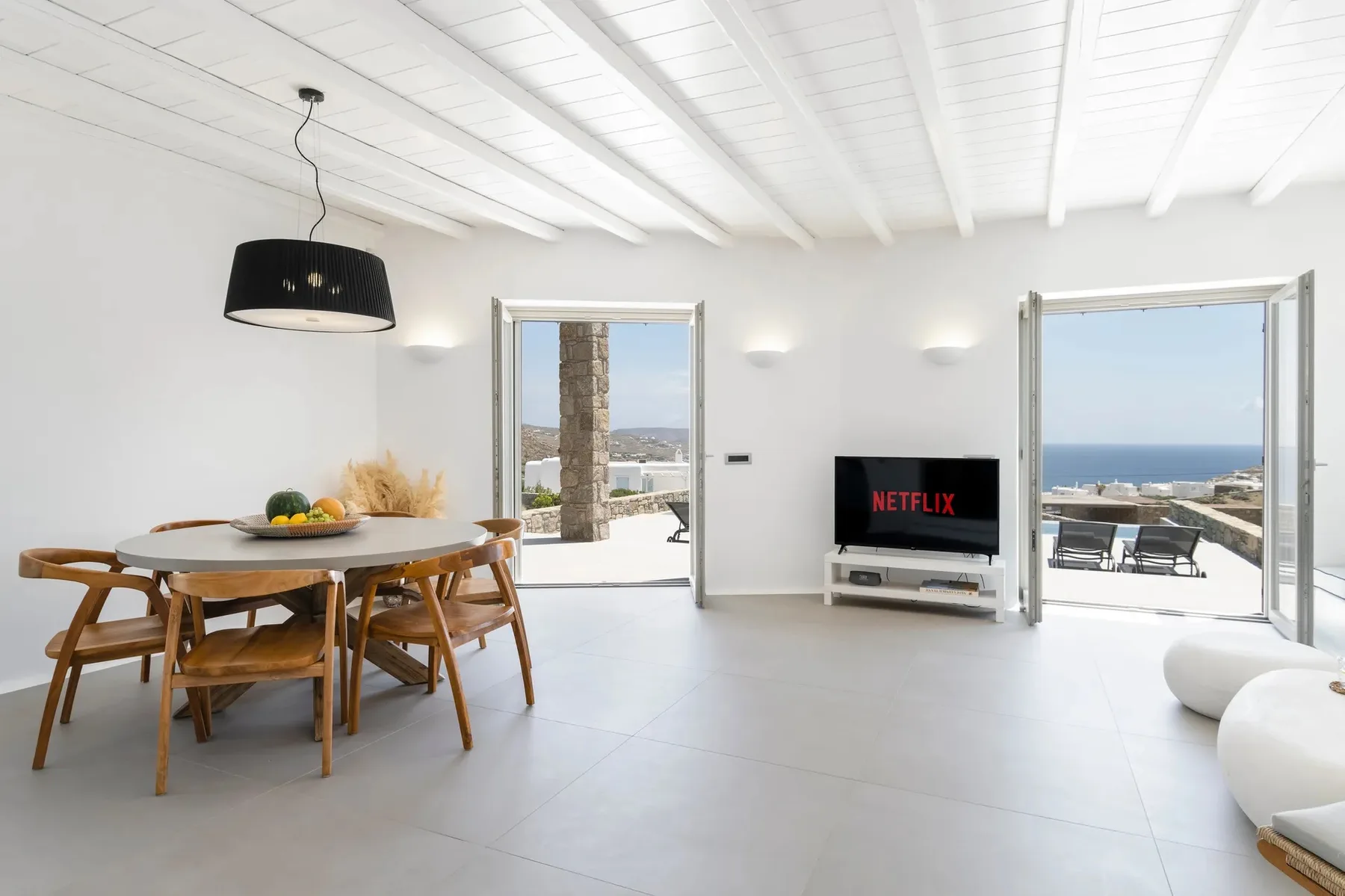 A bright open-plan living and dining area with a TV and sea views.
