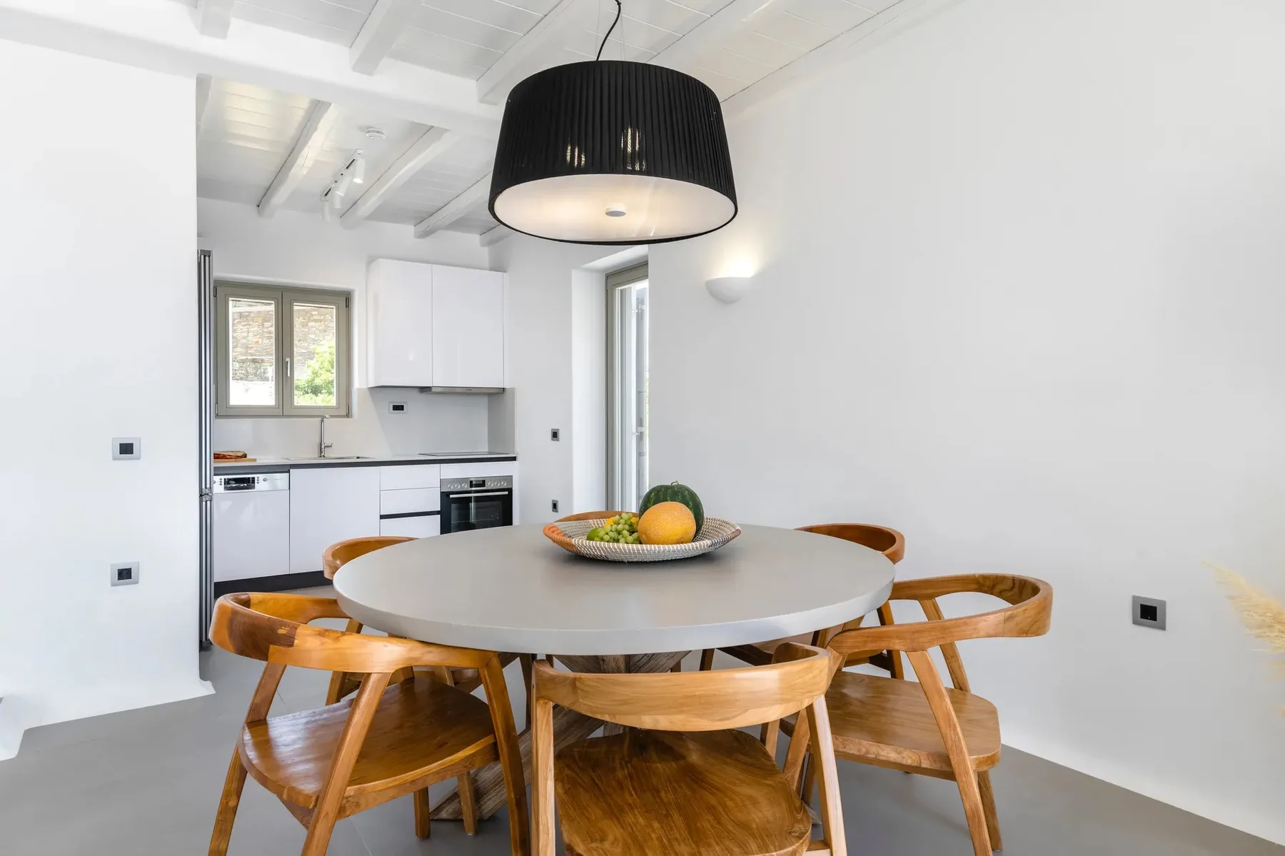 A dining area with a round table and a kitchen in the background.