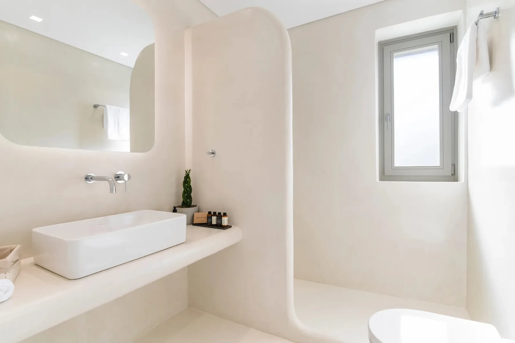 A bright bathroom with a vessel sink, wall mirror, and window.