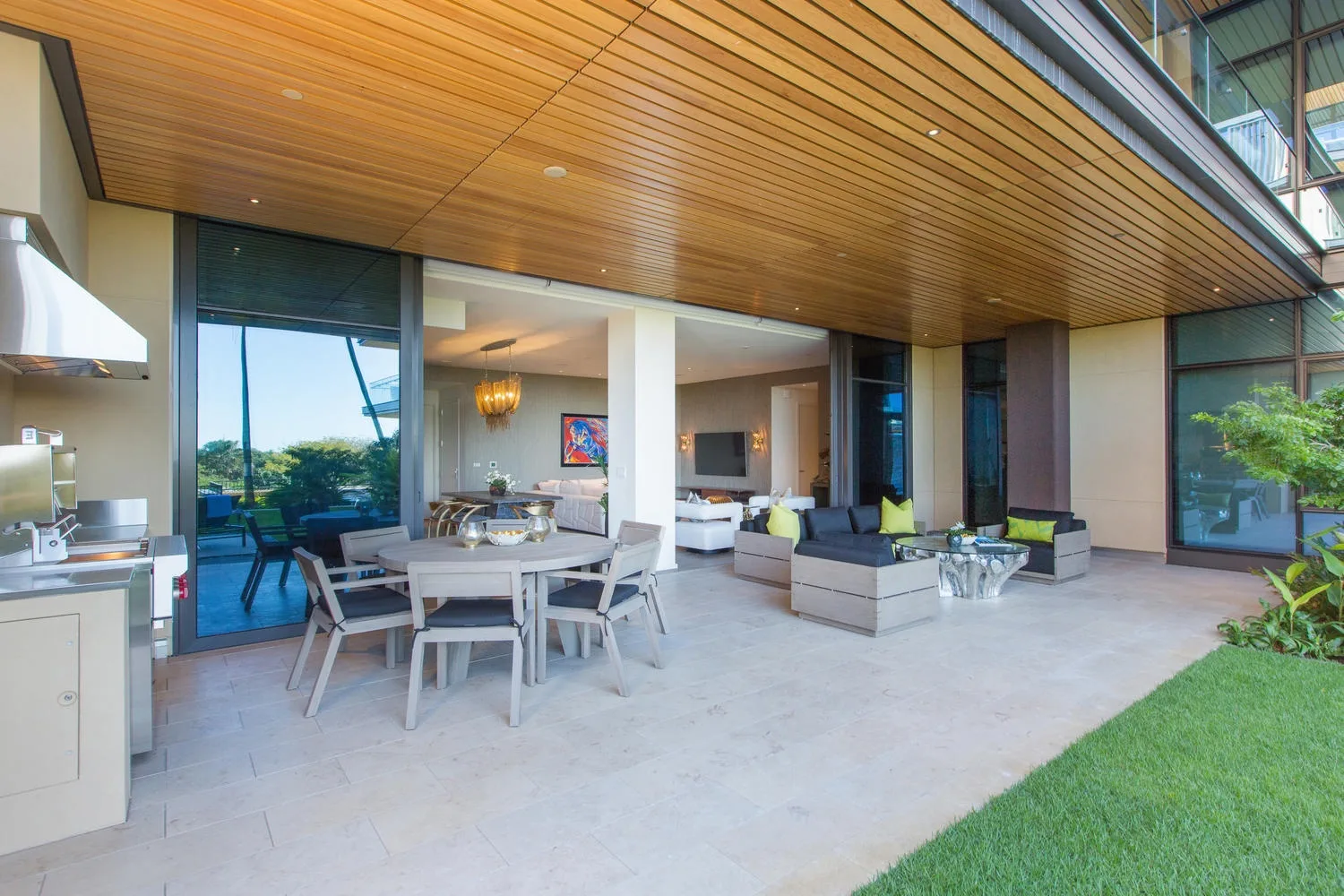A covered outdoor patio with dining and lounge seating beside the lawn.