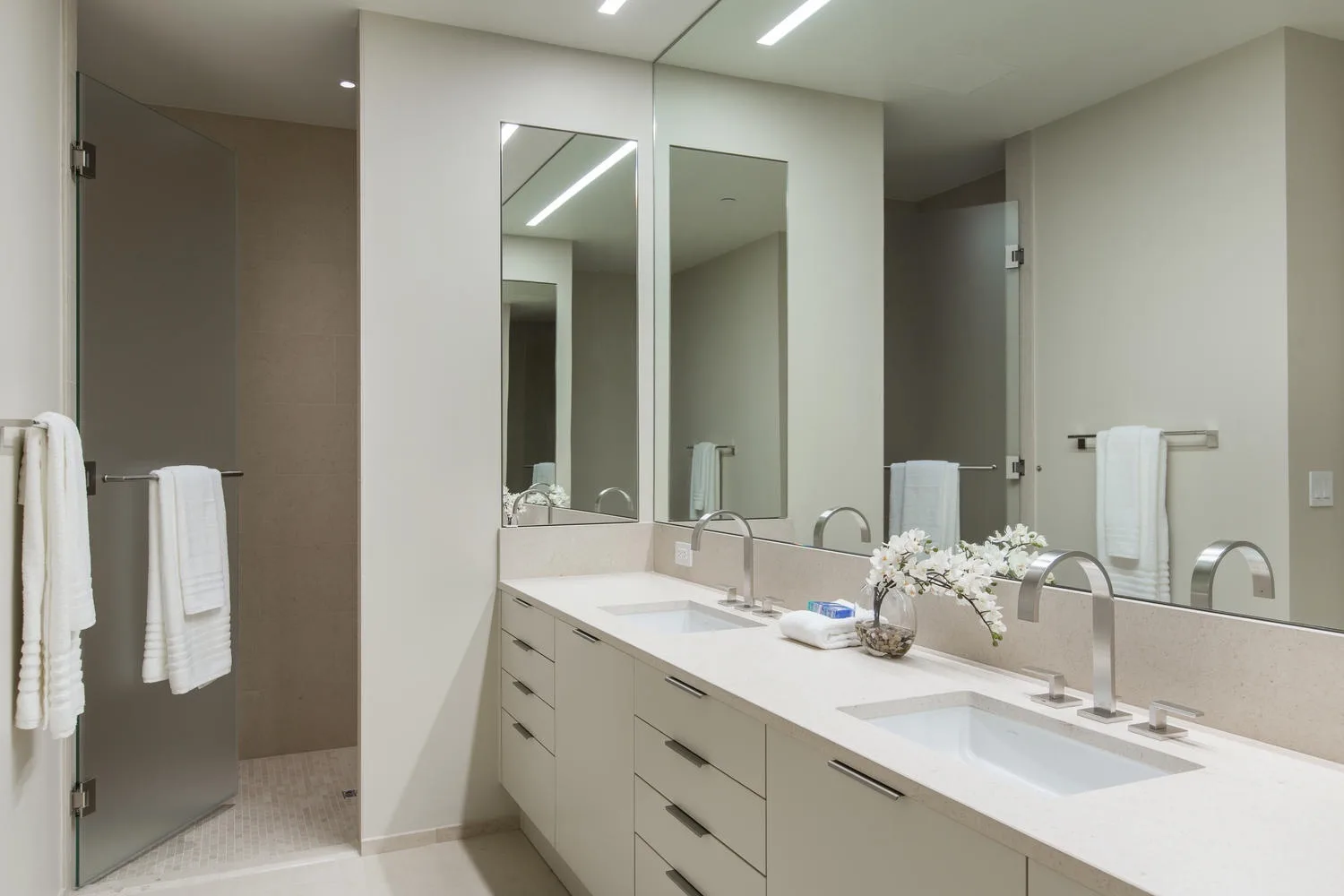 A bathroom vanity with two sinks, mirrors, and towels.