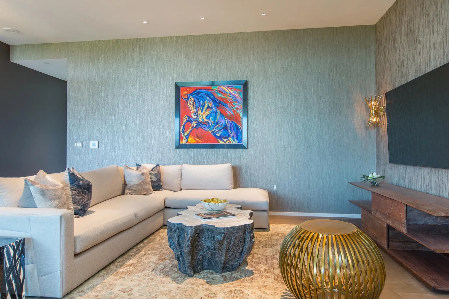 A living room with an L-shaped seating area, a coffee table, and colorful wall art.