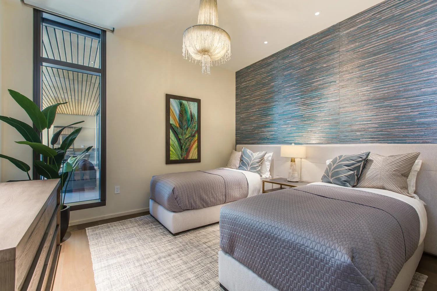 A bedroom with two beds, a bedside table, and a large patterned wall.