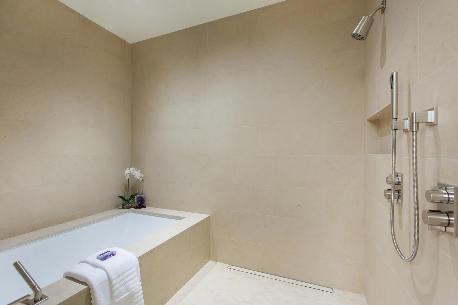 A tiled bathroom with a bathtub and a wall-mounted shower.
